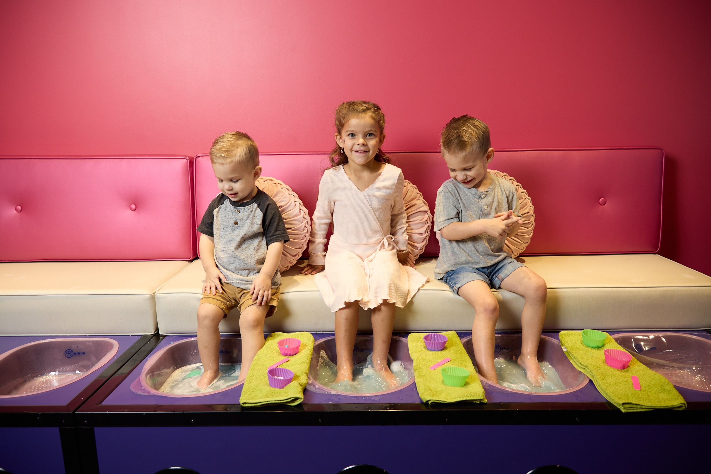 Three young children sit and enjoy a foot bath at Sweet & Sassy®, a salon and spa experience for kids. | Sweet & Sassy®