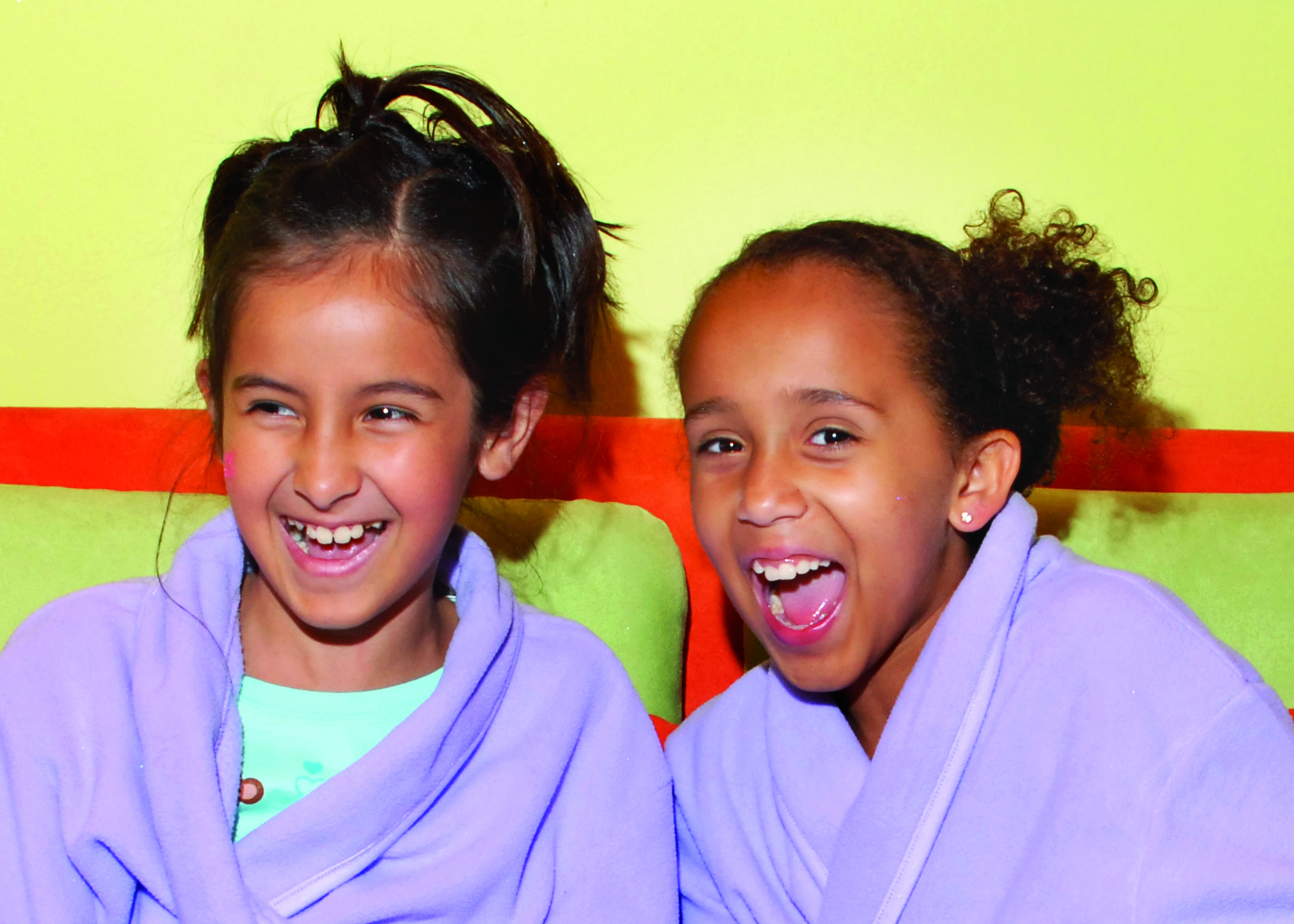 Two girls wearing robes laughing in spa for kids