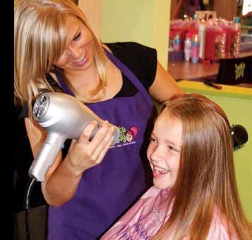 A young girl gets her hair blow dried by a salon worker. | Sweet & Sassy