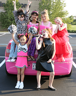 Six girls pose with a pink limo as part of a Sweet and Sassy birthday package